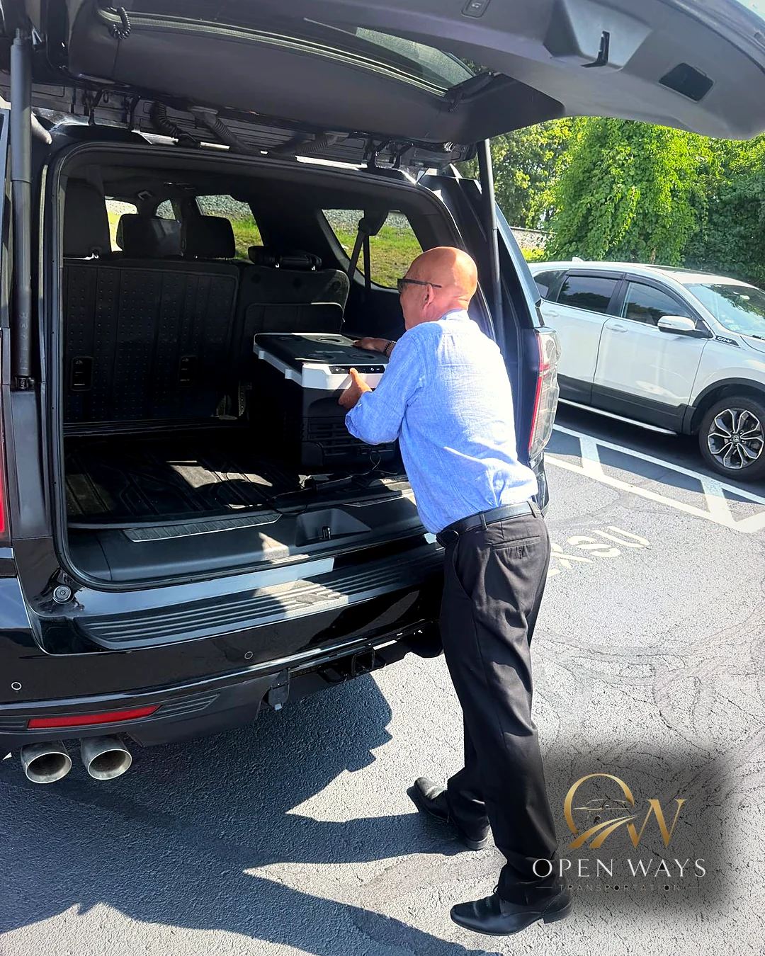 Joel loading a passenger's belongings into the back of the Open Ways executive SUV